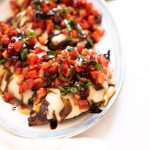 Grilled bruschetta chicken drizzled with balsamic glaze and served on a platter.